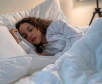 Latino beautiful woman lying down on bed in bedroom in dark night room.